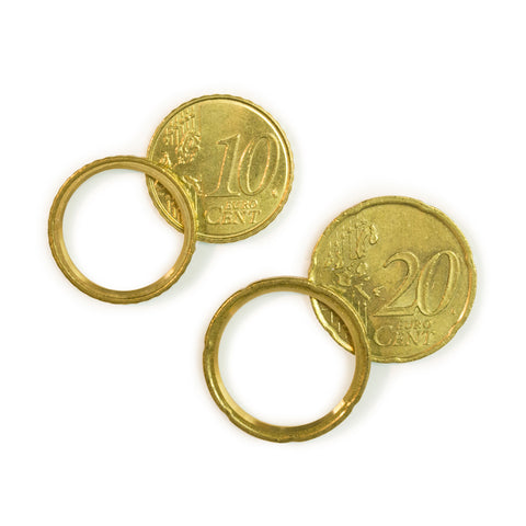 Two gold colored cooper bands lay side by side. Each is slightly overlapping with the coin from which is was carved out of.