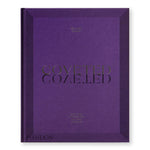 Purple book cover with gold debossed text "COVETED" at center, casting a sharp, mirrored, shadow below.