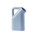 A pale blue jug with smooth rounded corners, a wide round mouth and tubular handle. 