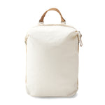A white medium sized backpack with a tanned leather top handle