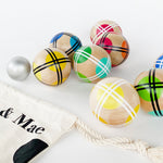 Close up of assorted rainbow bocce balls next to a cotton drawstring bag. 