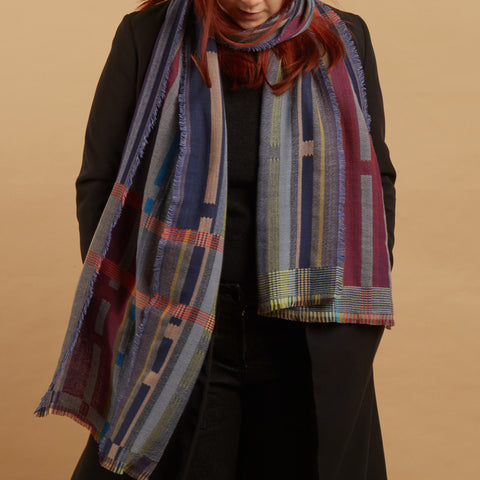 Person wearing a colorful plaid scarf against a beige background