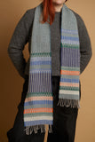 Person wearing a patterned scarf on a gray sweater with a beige background