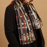 Person wearing a plaid scarf on a black jacket with a colored background