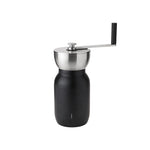 Sleek hand-crank coffee grinder with a black jar-shaped storage base and brushed stainless grinding bowl and handle with a black grip.