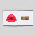 Interior book spread featuring a vintage, red, MTA hard hat, and a subway ticket dated Thurs July 16 1914 on the other.