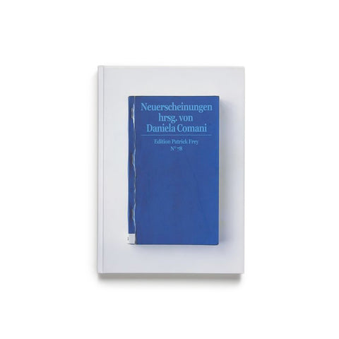 White book cover with photograph of a smaller blue book cover with light blue title near top