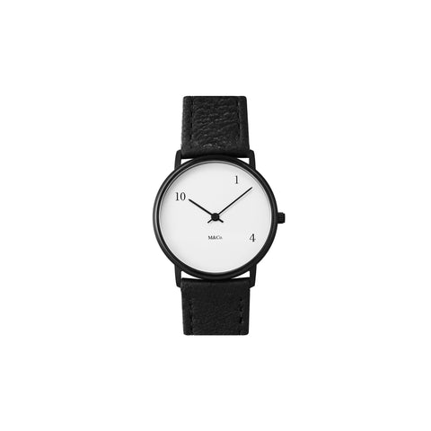 Front view of the 10-one-4 Watch. Around the face there are only three numbers, 10, 1, and 4, in black serif font. Aside from the numbers, the watch is minimal and classic with a black band, white face, black and thin black minute and hour hands. The black, serif M&Co logo is small below the hands.