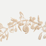 Close-up of a portion of a beige, single-strand lace necklace with watch spring and gear shaped pieces attached to it on either side, against a white background.