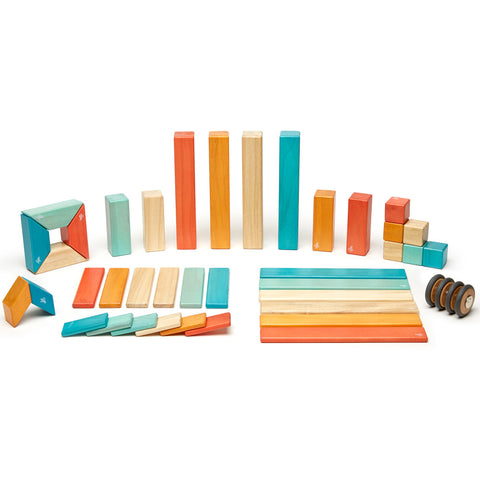 An entire set of 42 wood Tegu pieces laid out and grouped by shape.  The Sunset color pieces include turquoise, cream, yellow and orange.