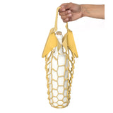An outstretched hand holds the handles of a small laser cut marigold-colored leather net bag, with a white wine bottle inside, its weight stretching the shape of the bag 
