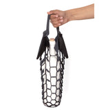 An outstretched hand holds the handles of a small laser cut black leather net bag, with a white wine bottle inside, its weight stretching the shape of the bag 