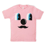 Light pink t-shirt with cartoon face. Two eyes, blue look off to the side, a circular nose and mustache with no mouth
