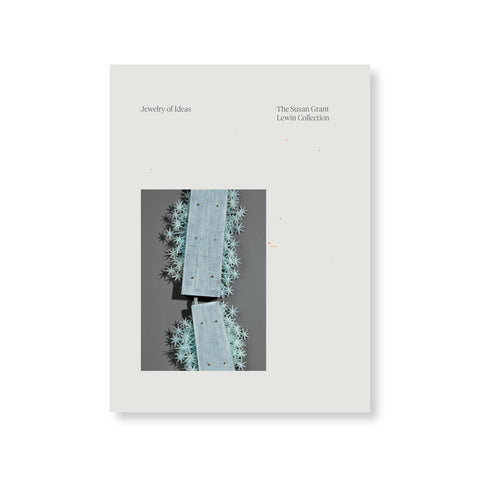 Light gray book cover with photograph in bottom left showing a light green jewelry piece. Title information printed above in small serif font.