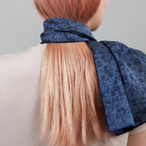 View from behind of the Made By Rain Scarf tied around the neck and long pink-blonde hair of a person.