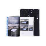 An open Concept Booklet on top of a Made by Rain book with a black cover with splashes of white. The Booklet is open to a two-page spread, titled “In the making” in white letters with text centered above a full page photo of rooftops beneath a cloudy sky. A large rectangular piece of fabric is positioned to collect raindrops on a roof.  The facing page is divided into three  photos with a text paragraph underneath; two show a crouching person checking on the process.