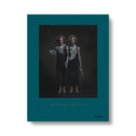 Teal book cover with photograph of long haired light skinned twins wearing black pants and tops and highly textured oversized jewelry peices around their necks and hands. Title in gold font at the bottom in serif font
