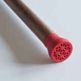 Close up of a cane foot. A small rubber material covers the end of the cane in red