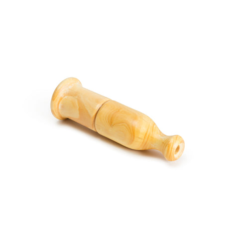 A duck bird call made of carved wood, the call is shaped like a tiny bell. The base of the call has a wide hole with a flared rim while the top has a smaller hole for blowing air through. There is a horizontally carved line at the center of the call.