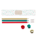 A Christmas Pencil set with the box and its contents laid out on a white surface. The shot includes a Christmas themed box, red gold and green pencils, and a white double sharpener. Pencil shavings in the shape of flowers are shown.