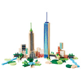 Against a white background is a photograph showing a frontal view of the building set. It is assembled to form a city scape including low buildings  of varying shapes and two skyscrapers. One skyscraper resembles Freedom Tower while the other is a simplified version of The Empire State Building. Integrated between buildings are several parks each featuring grassy areas, trees and water.