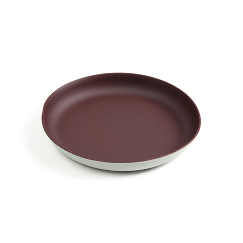 A medium-sized plate featuring a dark red matte interior and white matte exterior. The rim of the plate is extended upward allowing for a deep dish styled plate good for gravy and other runny foods.