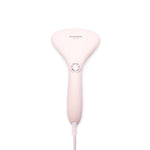 The Cirrus Steamer in pale pink with a matte finish. The steamer features a wide upper body and a long slim handle. The power button is placed at the very top of the handle and is wide and round. The power hangs below, attached to the handle.