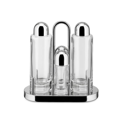 Viewed straight on: minimal, post-modern, stainless-steel condiment caddy with four cylindrical empty glass vessels, two tall flanking two smaller, each with a rounded stainless steel cap.