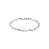 Silver-colored bangle with the word "PEACE" engraved in different languages around the outside.  "Article22 :: PEACE BOMB" is engraved on the inner side of the bracelet. 
