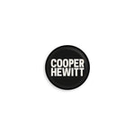 Round hemp paper textured button with a black background and the Cooper Hewitt logo in white.