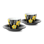 A pair of floral printed espresso cups and saucers. Each cup features a yellow floral print on a black and white background. The saucers are black