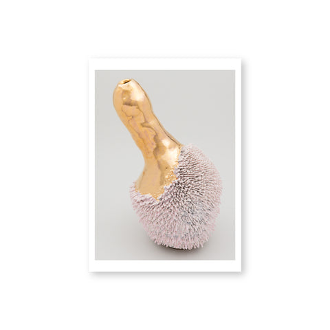 A phallic shaped gold ceramic vase. The bottom of the vase is covered in a pink fungi like texture.