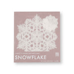 A lacy paper snowflake shows through clear packaging with a pink cardboard backing.
