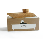 Contraband Cork Speedboat placed on top of its cardboard box packaging. The packaging includes an image of a speedboat depicted in black over a white tub shape with black text centrally located reading 'DMFD New York'.
