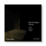 A dark book cover featuring an image of Adjaye's project. Most of the cover is black, the only the floor and the right wall is visible. The title and publisher's logo is designed using white font.  