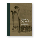 A rectangular book cover, taupe with a full-length strip of dark green, textured binding on the left, and a sepia toned photograph showing the curvy iron art nouveau railings, entranceway and signage for a Paris Metro station against a pale image of a multi-story apartment building in the background. The book’s title appears to the left of one of the sign supports in four lines of white text. 