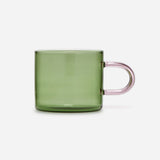 Low glass mug with a straight-sided green bowl and a delicate, elongated, pale-pink handle.