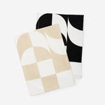 Two folded dishtowels with the same checker-wave pattern, one in a beige-and-white colorway, the other black-and-white.