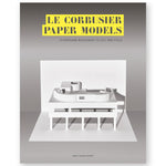 Book cover featuring an all-white paper model of the modernist home Villa Savoye, designed by famed architect Le Crobusier. the model display sits in a dark grey to light grey gradient background. The title is centered at the top of the book cover, using a cut-out font with yellow edging.