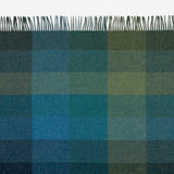 Checkered throw with fringe tips in an array of shades of green.