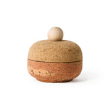 Squircle shaped container with equally proportioned cork lid and pink cork bottom with a sphere-shaped maple wood handle, shot on a white background.