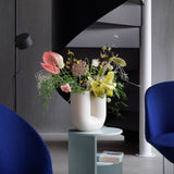 A Kink vase filled with flowers is shown in a contemporary room setting.