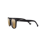 Side angle view of the Ruta Sunglasses Black/Caramel, which have black, rounded square-rectangular frames, and caramel lenses. The Parafina logo, two line waves, is printed in silver on the temple of the right arm.