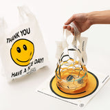 On the left, a smiley face bag which says Thank You and Have A Nice Day next to a PlasticPaper mesh bag held by a hand, containing a clear glass bowl, over a printed, unopened flat, square renewable bamboo bag. 