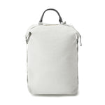 A light grey medium sized backpack with black leather top handle.