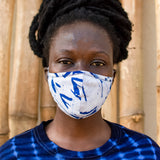 Model wearing a face mask made of a pale blue fabric printed with indigo floret silhouettes, and a navy tie dyed shirt.