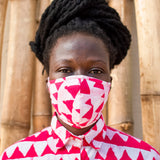 Model wearing a face mask printed with repeating rows of vibrant pink triangles, and a matching collared shirt.