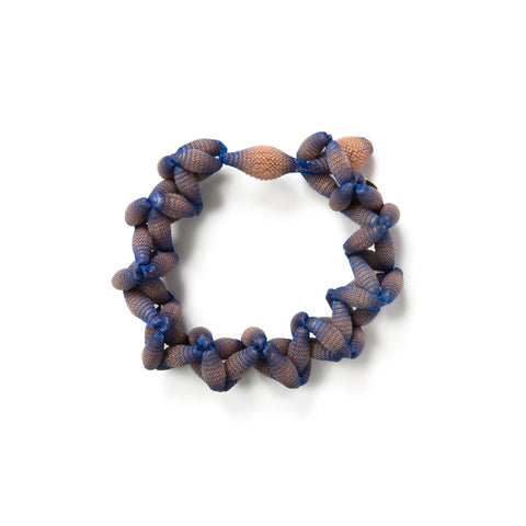 Several desaturated orange silicone beads incased in blue lace form a bracelet with a loop closure