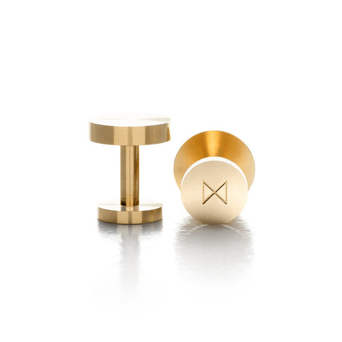 A pair of solid brass cufflinks. The brand's logo is etched into th base of the cufflink.