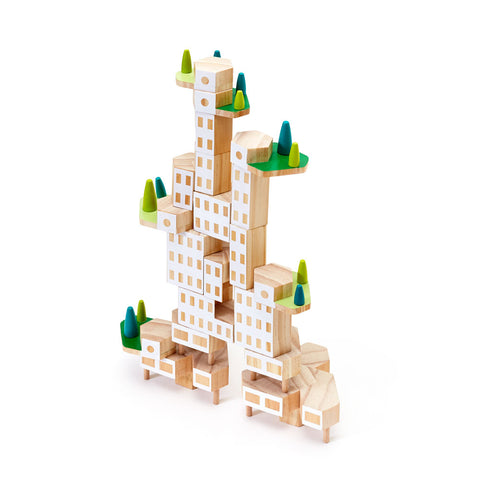 On a white background an angled image of an assembled unfinished wood building block set. It is put together to form one building but with various sized hexagonal shaped blocks forming two asymmetric towers. Six elevated platforms that look like mini terraces are staggered throughout the structure and have green surfaces with trees.